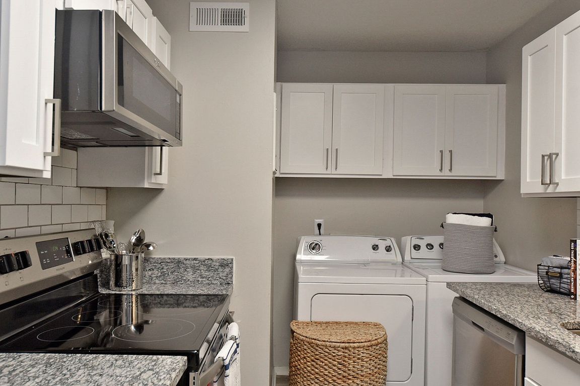 Kitchen with granite counters, washer & dryer, modern cabinetry, and stainless appliances