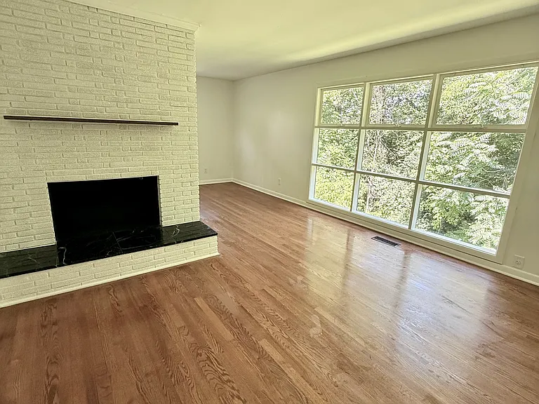 Main living area with newly refinished solid hardwood floors and large windows bringing in ample natural light.