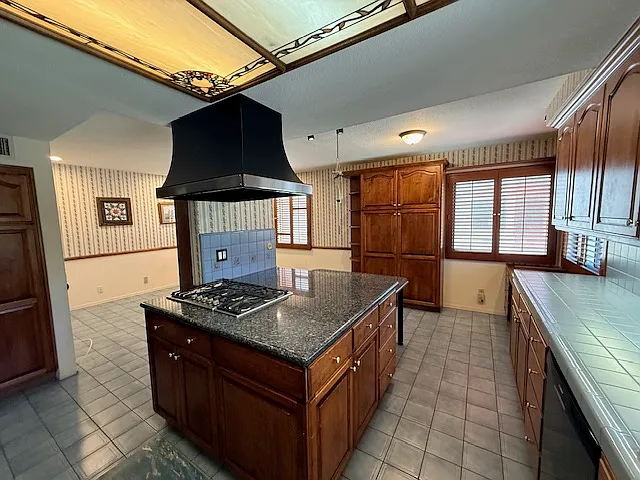 Kitchen features a island with cooktop and multiple pantry cabinets.