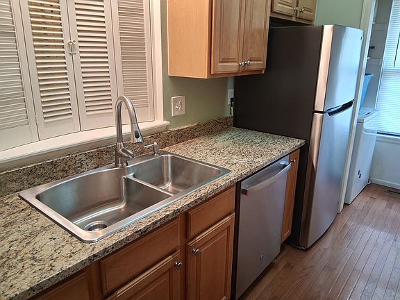 New granite countertop, new SS sink and modern faucet, manufactured wood floor and laundry room next to the refrigerator.