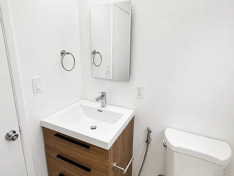 Modern bathroom vanity with wood-tone cabinetry, bright lighting, and updated fixtures.