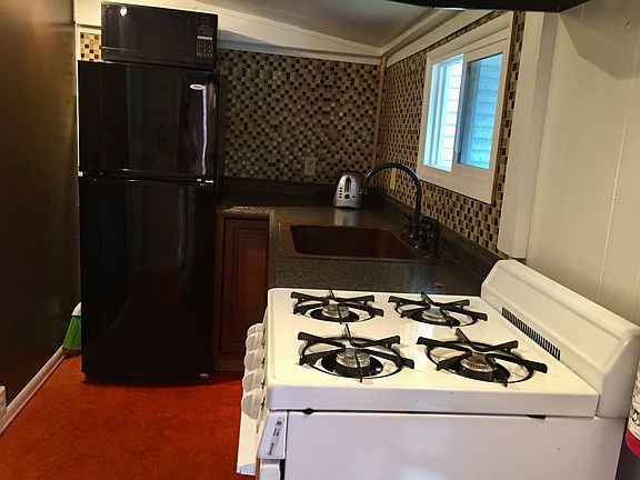 Galley kitchen with copper sink and glass back splash .