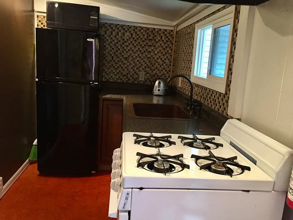 Galley kitchen with copper sink and glass back splash .