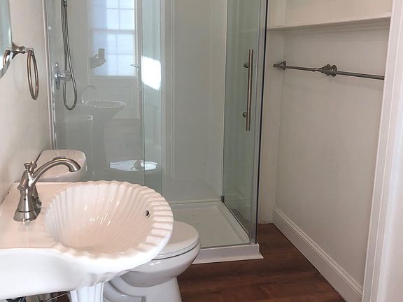Bathroom with vintage pedestal sink and new glass shower enclosure.