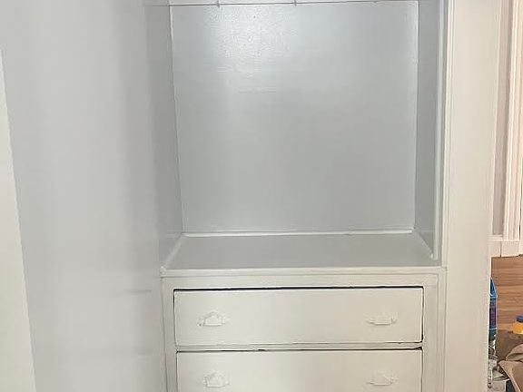 Down the short hall (living room to the right) is a coat rack with built-in drawers for storage