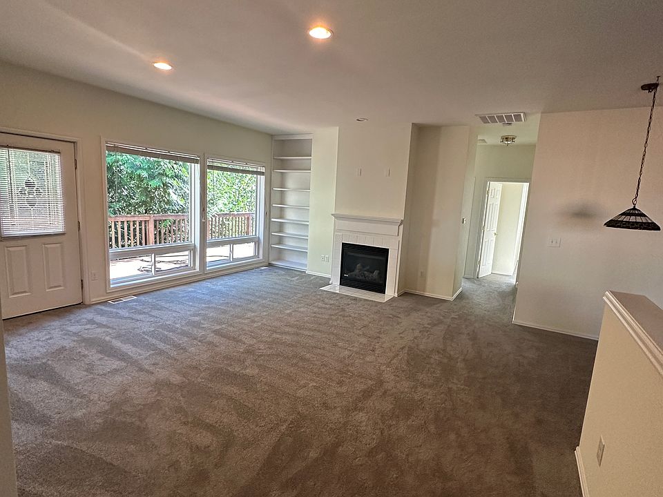 Full view of living room with fireplace, including floor to ceiling windows with view to deck.