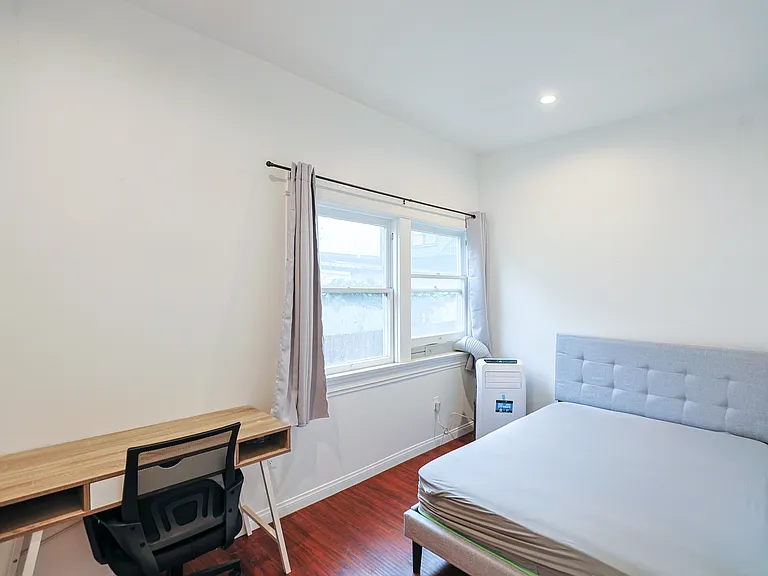 bedroom two window, bed, desk, chair, and individually controlled heating/ac unit