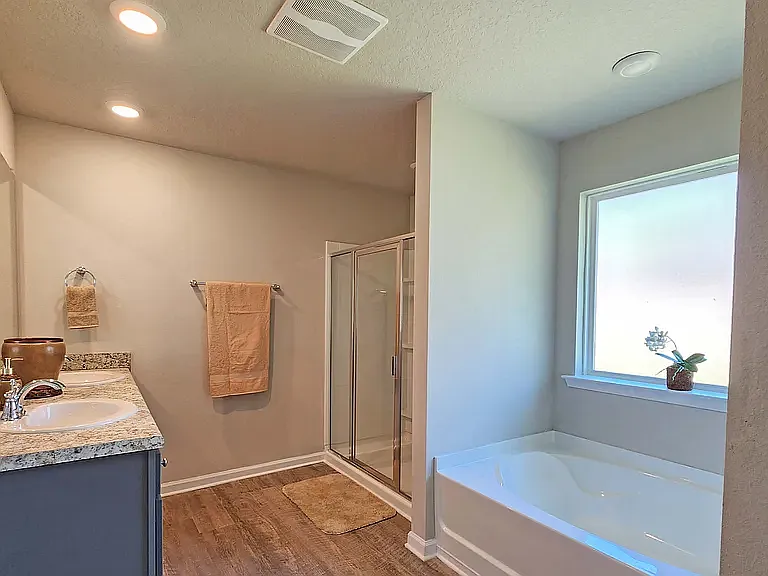 Primary bathroom includes two side-by-side sinks & mirrors, large bathtub, and shower. Linen closet and cabinets & drawers under the sinks for storage.
Toilet located in water closet within this large bathroom.