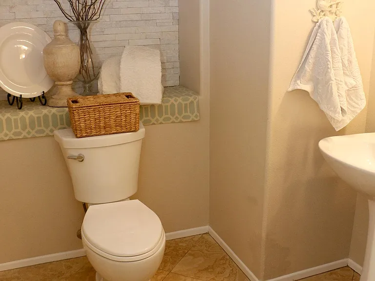 Downstairs 1/2 bath with stone wall cut out, pedestal sink, and Peruvian Travertine tile floors.