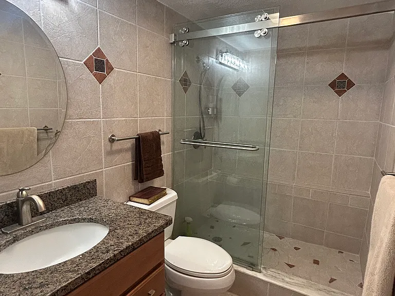 View of granite countertop vanity and walk in shower