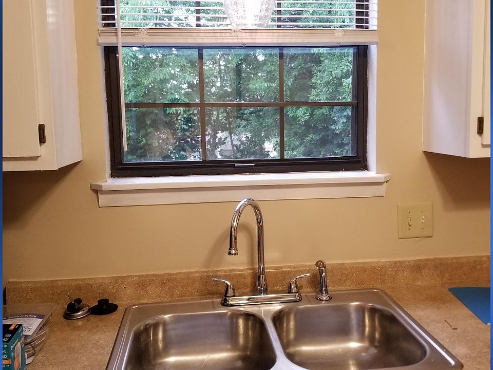 Kitchen sink with outdoor view & pendant light above.