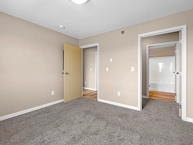 Step into the inviting interiors of Minot Place Apartments, featuring spacious layouts and modern finishes. This carpeted room is perfect for your personal touch. Ready to make it your own? Schedule a tour today and see for yourself!