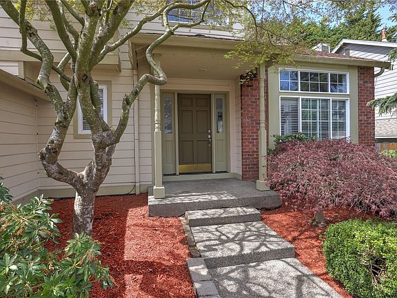 Established landscaping surround the covered front porch offers a welcoming feel.>