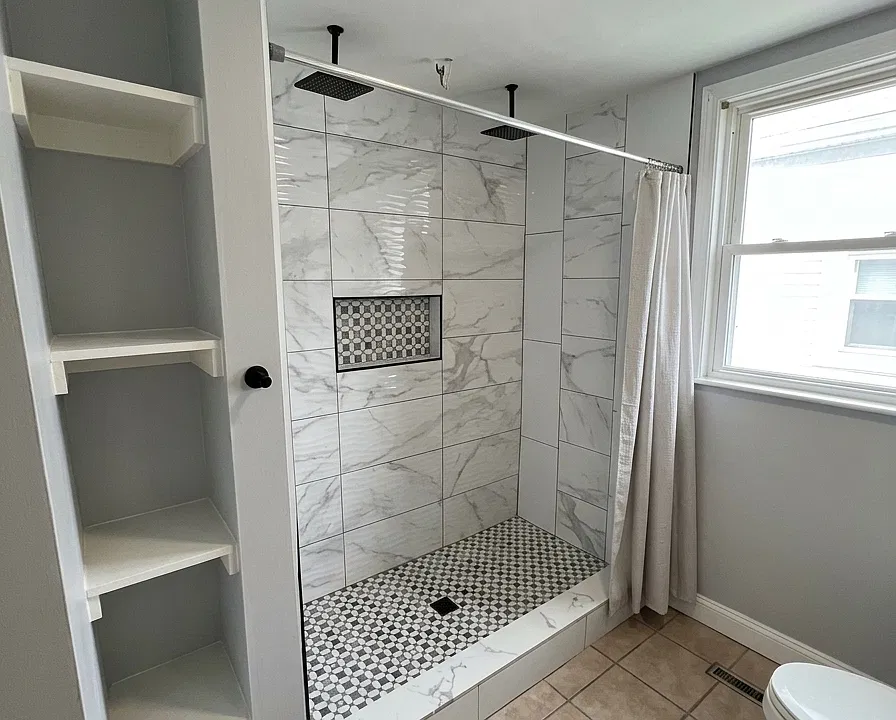 Bathroom. His & Her Shower. Updated full bathroom featuring an oversized tiled shower with multiple shower fixtures, built-in niche, and modern finishes.