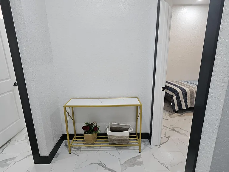 Hallway area with console table for easy drop-zone storage leading to bedroom 1, private bathroom and common space.