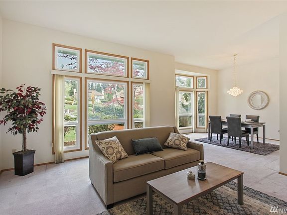 Another view of the living room and gorgeous dining room with walls of windows looking out to established landscaping. 