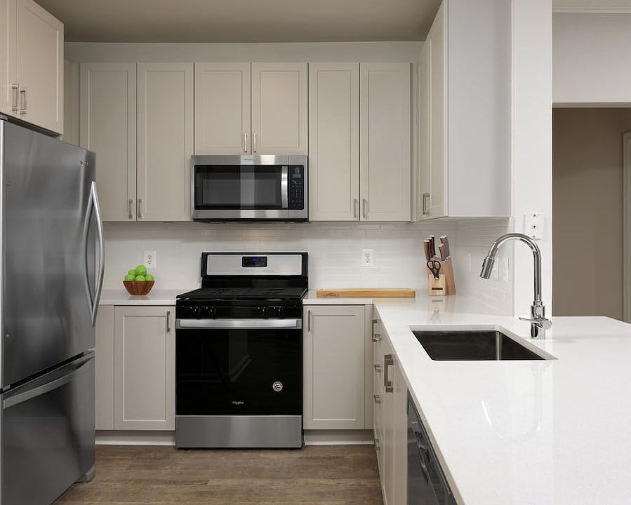 Renovated II kitchen with grey cabinetry, white quartz countertops, stainless steel appliances, white tile backsplash, and hard surface flooring