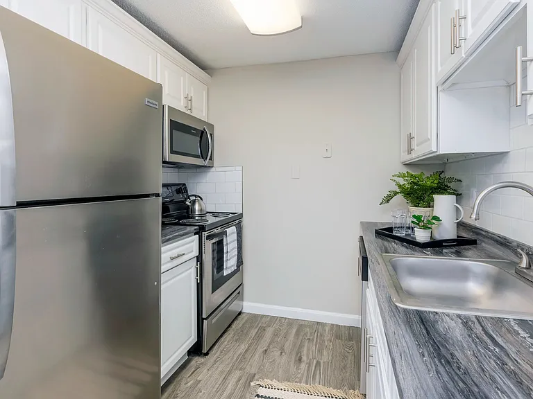 Indulge in modern elegance in The Sycamore Kitchen, boasting black fusion countertops, white cabinetry, and a stylish white subway tile backsplash.