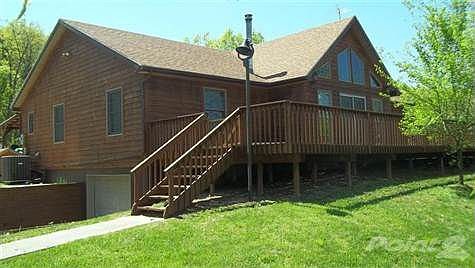 Side view of the home showing the full basement and the deck with the stairway as an entrance.