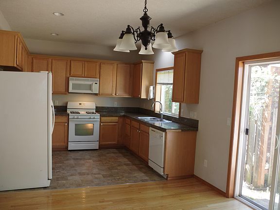 View from dining room of kitchen, sliding door to patio, yard. Gas oven/stove, microwave, refrigerator with ice maker, water.