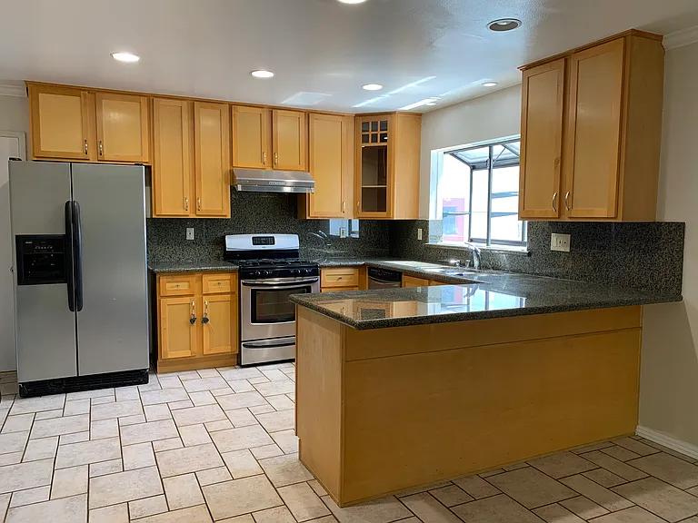 Bright kitchen with granite countertops and full-height granite backsplash