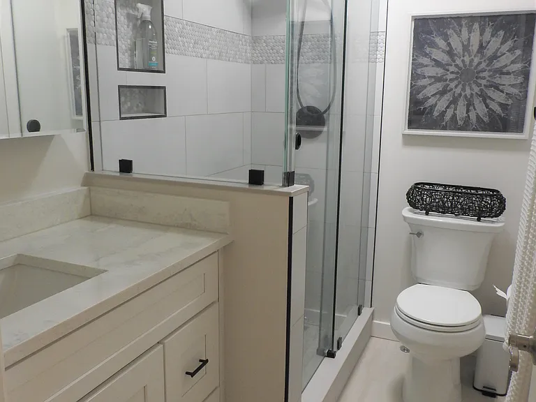 Beautiful new guest bath room with glass surround shower, porcelain tile floors and marble countertop.