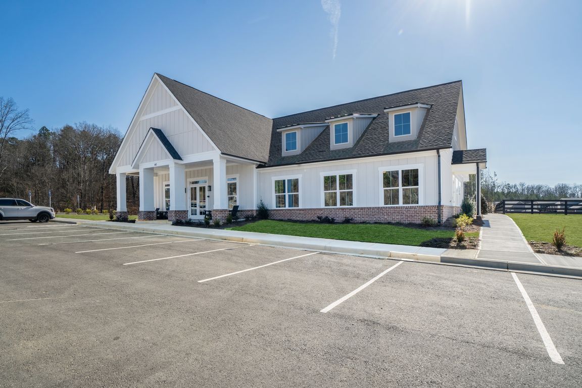 Clubhouse exterior with ample parking and rocking chairs on the front porch.