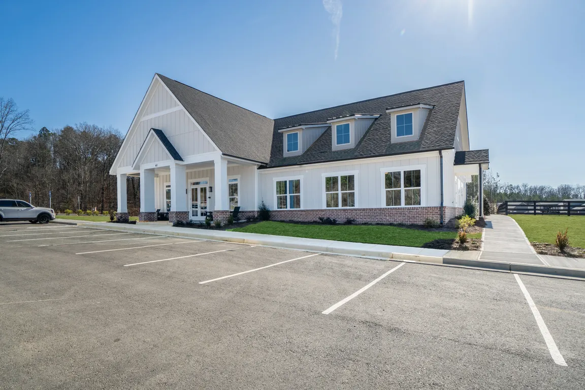 Clubhouse exterior with ample parking and rocking chairs on the front porch.