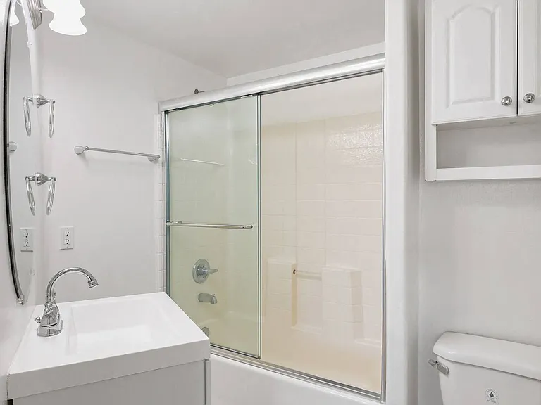Bathroom with Bathtub with Glass Doors and Additional Storage Cabinet