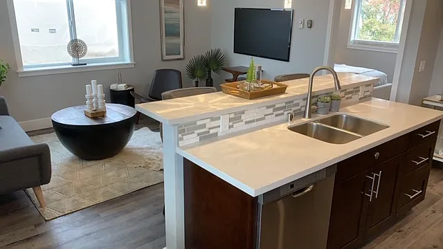 Island Bar with stainless steel sink and whisper quiet dishwasher, quartz countertops and tile backsplash.