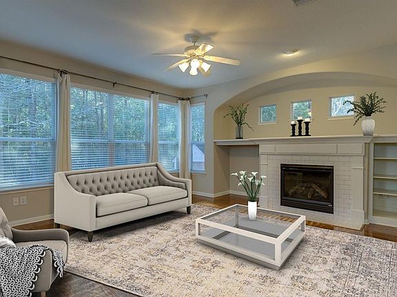 Living Room offers warmth of a gas-log fireplace with tile surround, built-in display shelves and wood flooring.