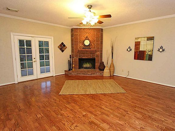 The corner, brick fireplace is the heart of the room.  French doors lead to the backyard.