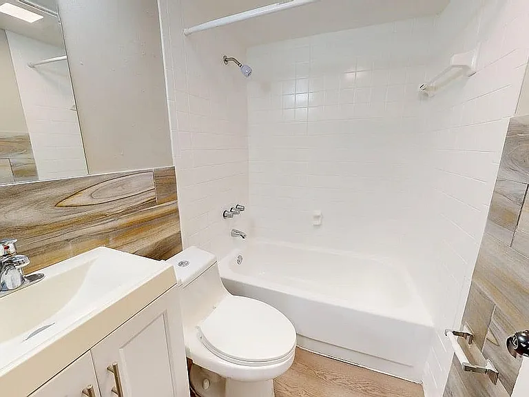Modern bathroom featuring a sleek vanity, elegant wood-accented walls, and a pristine bathtub with bright tiles.