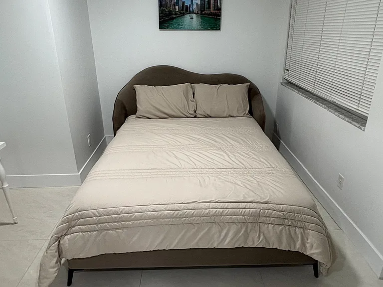 Private bedroom with a full bed, tiled floors, and a window with blinds for light control and privacy.
