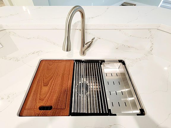 Quartz countertops and backsplash throughout kitchen, special sink with other accessories, garbage disposal and plenty workspace.