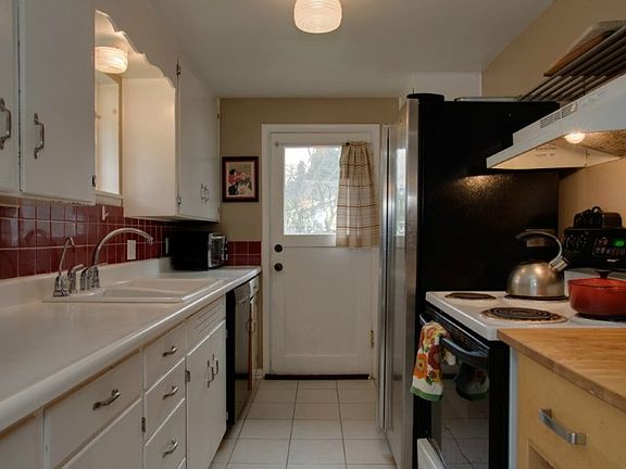 Galley kitchen with good cabinet space, tile floors, tile back splash & window over sink. Door leads to side of home for easy access to kitchen...great for grocery shopping!