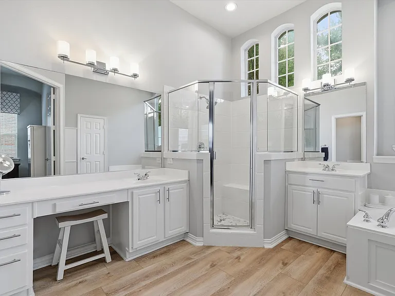 Primary bathroom with separate vanities, walk-in shower, soaking tub, and large walk-in closet.
