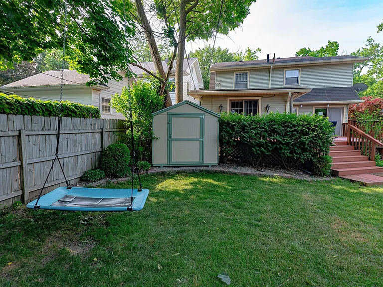 Back yard with storage shed and deck behind the hedge