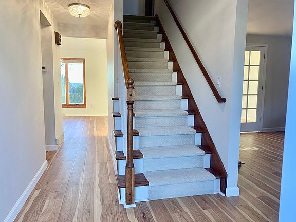 Main entry way with two crystal chandelier light fixtures, brand new stair runner to second floor, and natural Hickory flooring throughout.