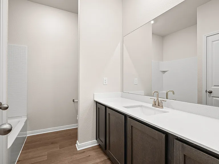 The secondary bedroom has a sprawling vanity and shower-tub combo.
