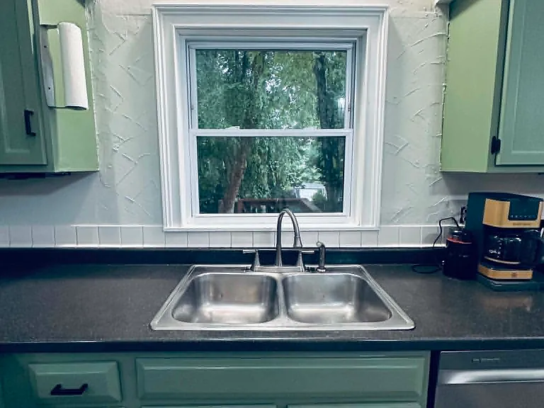 Beautifully renovated kitchen featuring updated cabinetry, a new dishwasher, and a new refrigerator. The open layout overlooks a private, nature-filled backyard, offering peaceful views while cooking, dining, or entertaining.