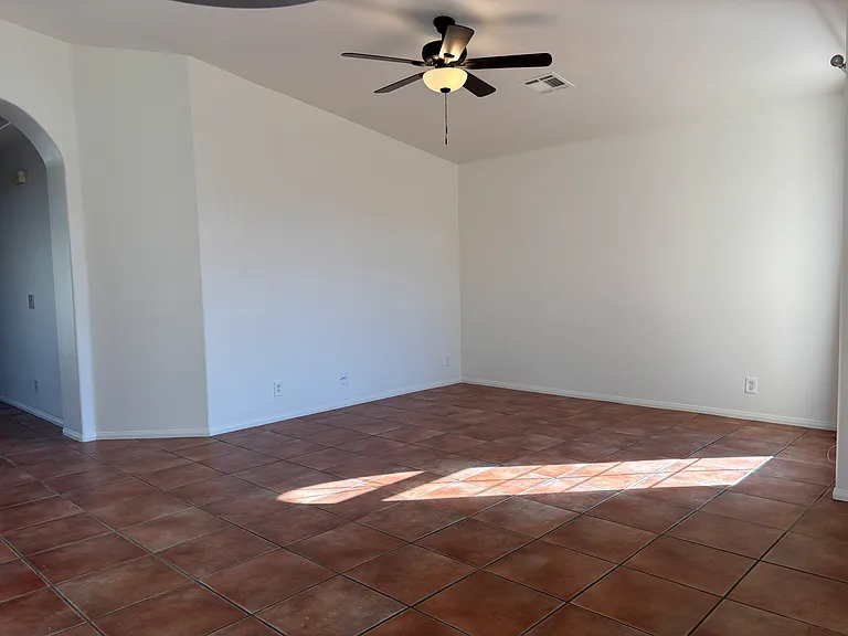 Spacious living area with ceiling fan, high ceilings, and plenty of natural light.