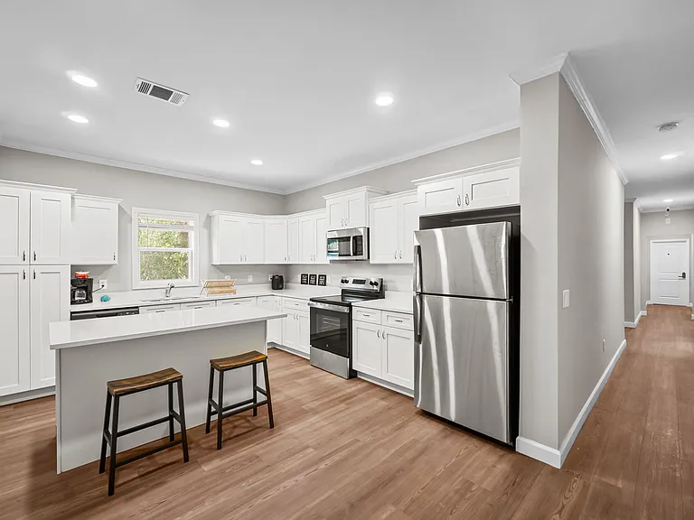 Open kitchen with white cabinetry, stainless steel appliances, and a large peninsula with seating for casual meals.