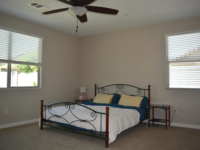 Primary bedroom has window looking to trees and bushes in backyard