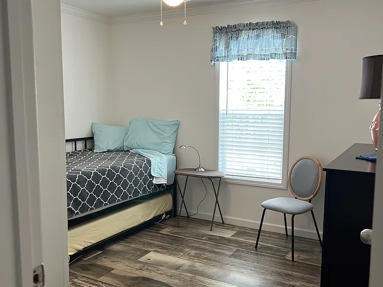 Bedroom with trundle bed, dresser, ceiling fan.