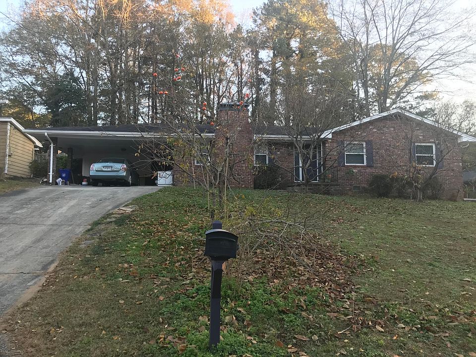 Front of house with double carport & storage room . Notice orange persimmon fruit on tree!