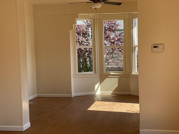 Looking into the living room from dining room. Blinds are on all windows. Very light and bright.