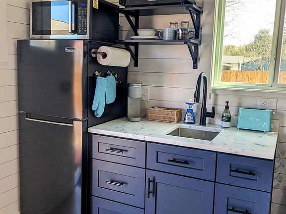 Kitchen with full sized refrigerator, 3-in-1 convection microwave oven, full sink and garbage disposal, coffee maker, and two burner cooking appliance.