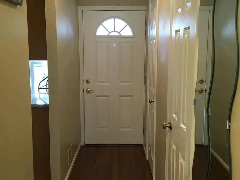 Corridor to front door with kitchen on left and powder room