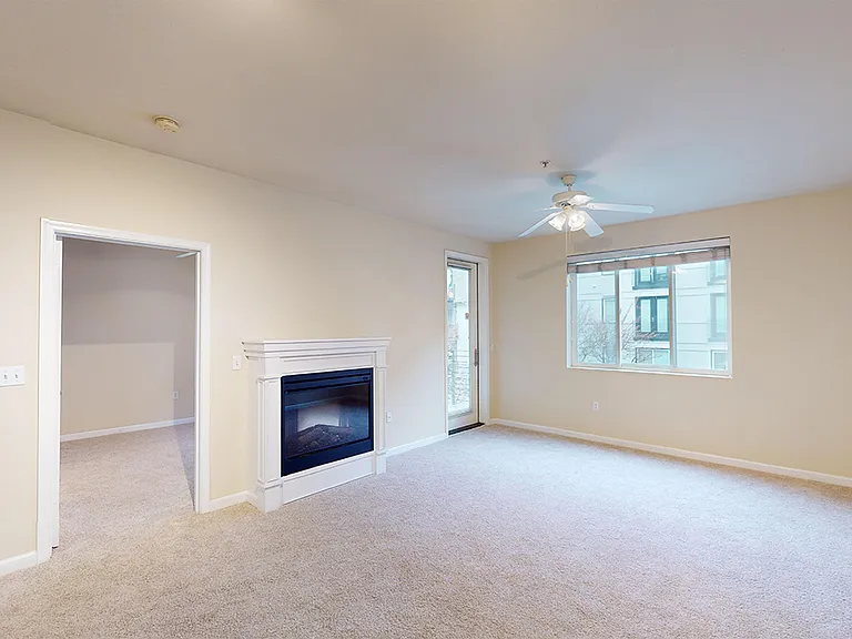Apartment living room with plush carpet flooring and fireplace in select homes.